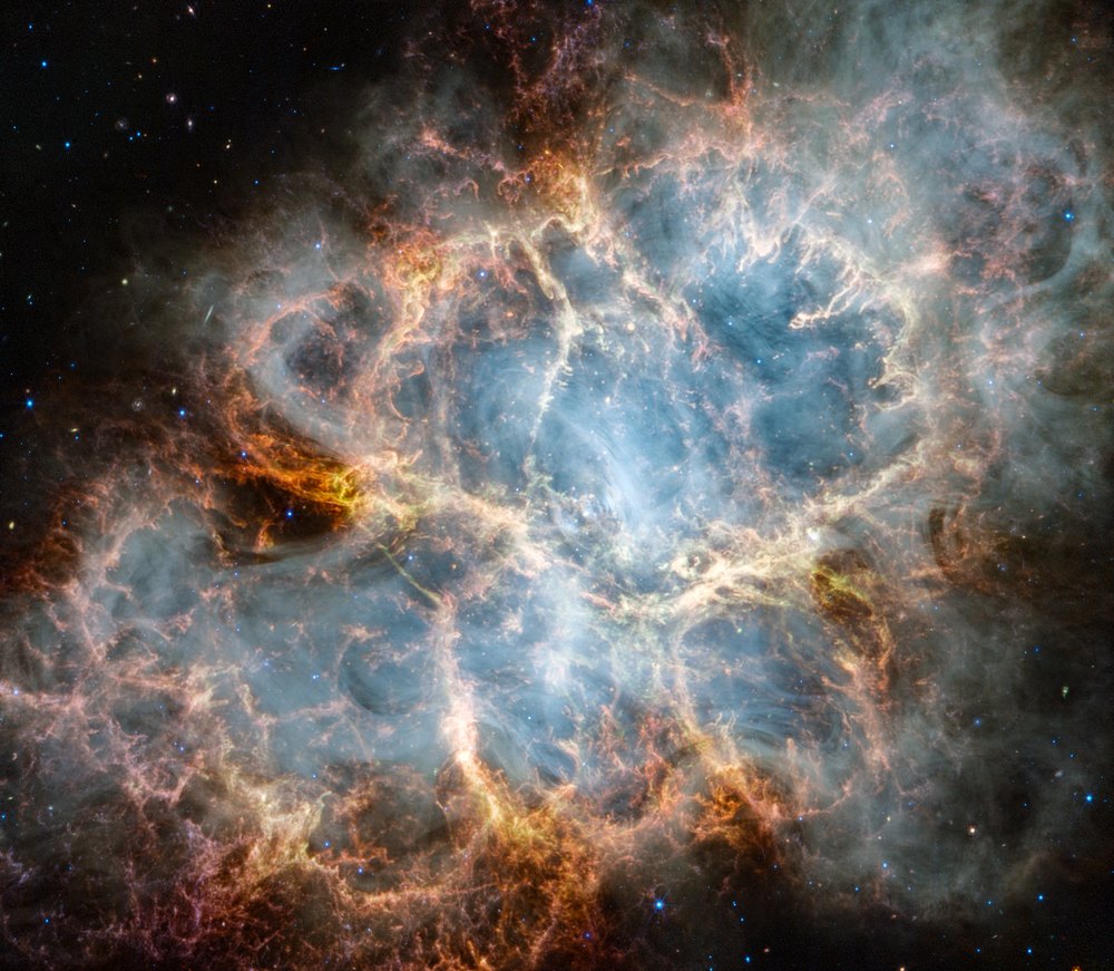 The Crab Nebula photographed by Webb, its orange filaments and blue glow filling the frame to the edges